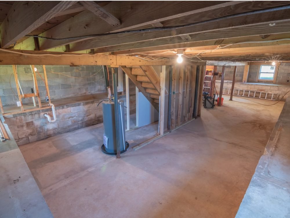 Dehumidifier running in a home basement with a hose draining condensed water continuously into a nearby floor drain